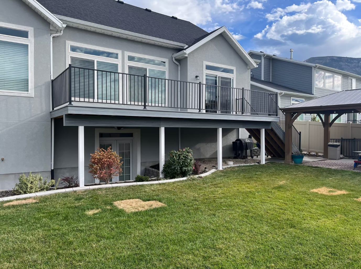 Wide elevated composite deck with black metal railings overlooking a Utah backyard