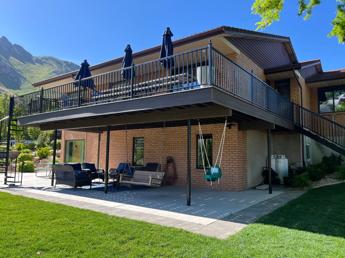 Two-story Trex composite deck with black aluminum railing and Wasatch mountain backdrop in Utah County
