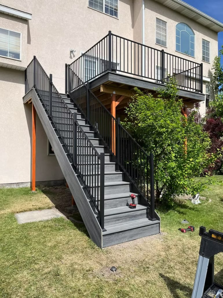 Multi-level Trex composite deck staircase with black aluminum railing — Utah residential build
